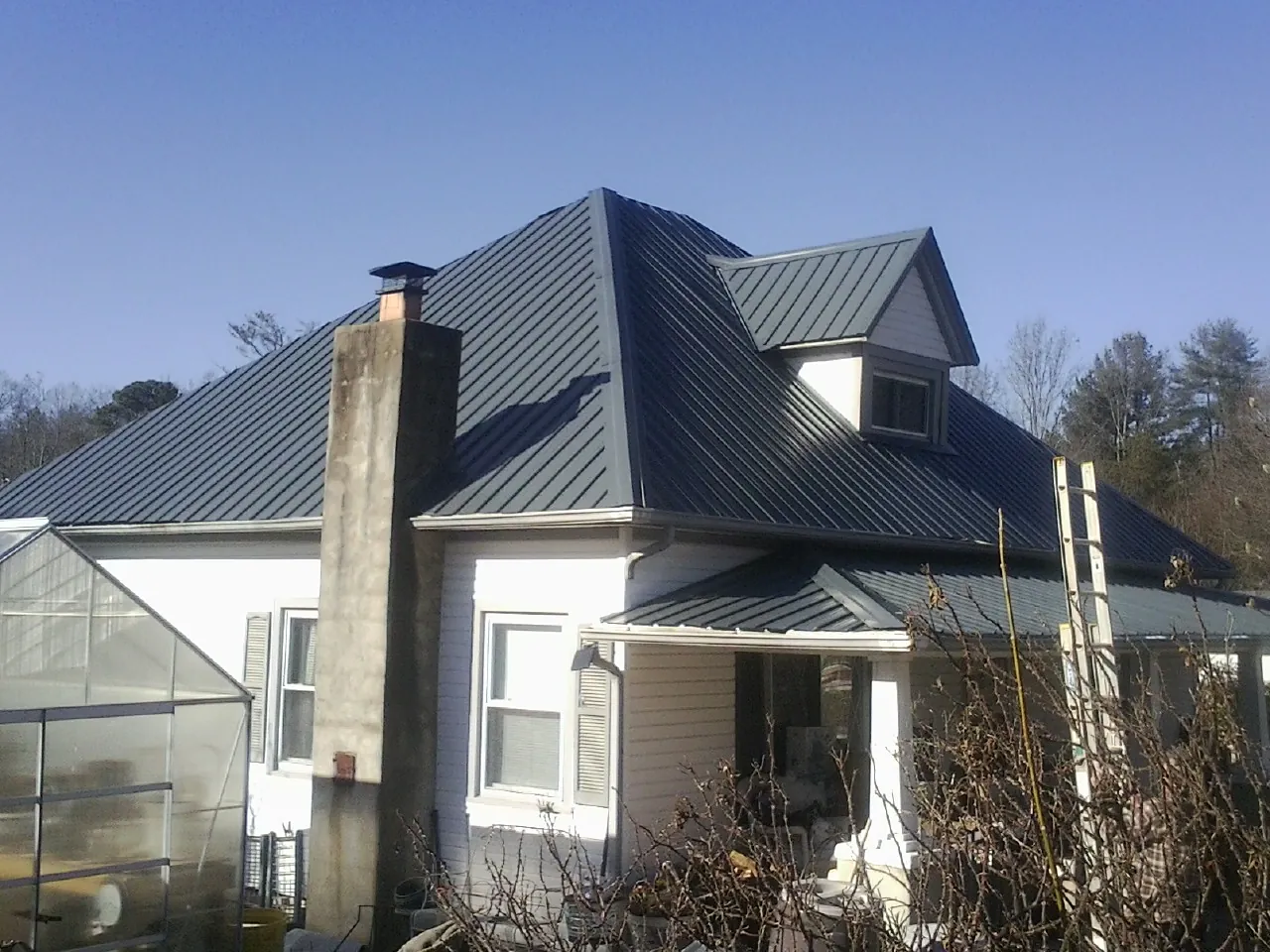 Dark blue standing seam metal roof on a white farmhouse with dormer — Slate & Tile Roof Repair by Roofing Brothers in Ramona