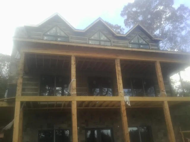 Dormers and porch framing on a large log home under construction — Roof Coating work by our crew in Ramona